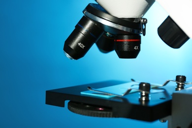 Photo of Modern microscope with different lenses on color background, closeup. Chemical research