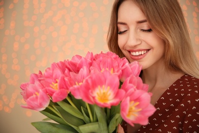 Photo of Portrait of smiling young girl with beautiful tulips on blurred background. International Women's Day