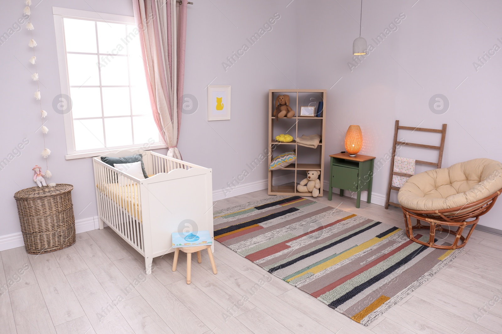 Photo of Baby room interior with comfortable crib and papasan chair