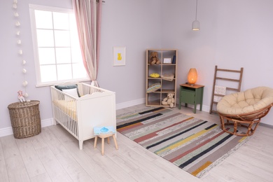 Photo of Baby room interior with comfortable crib and papasan chair