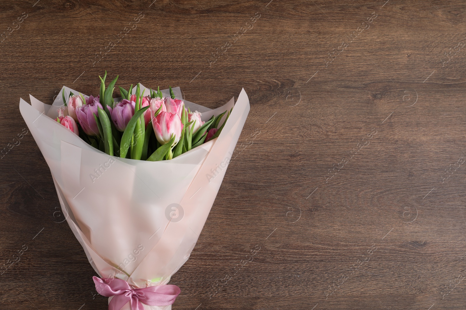 Photo of Bouquet of beautiful tulips on wooden table, top view. Space for text