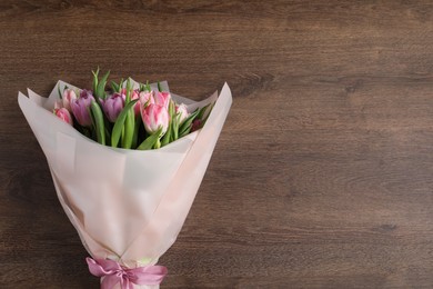 Photo of Bouquet of beautiful tulips on wooden table, top view. Space for text
