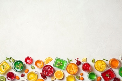 Flat lay composition with different jelly desserts on light background, space for text