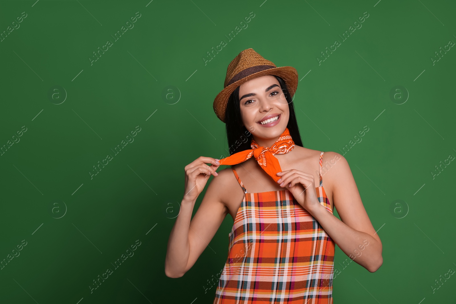 Photo of Fashionable young woman in stylish outfit with bandana on green background, space for text