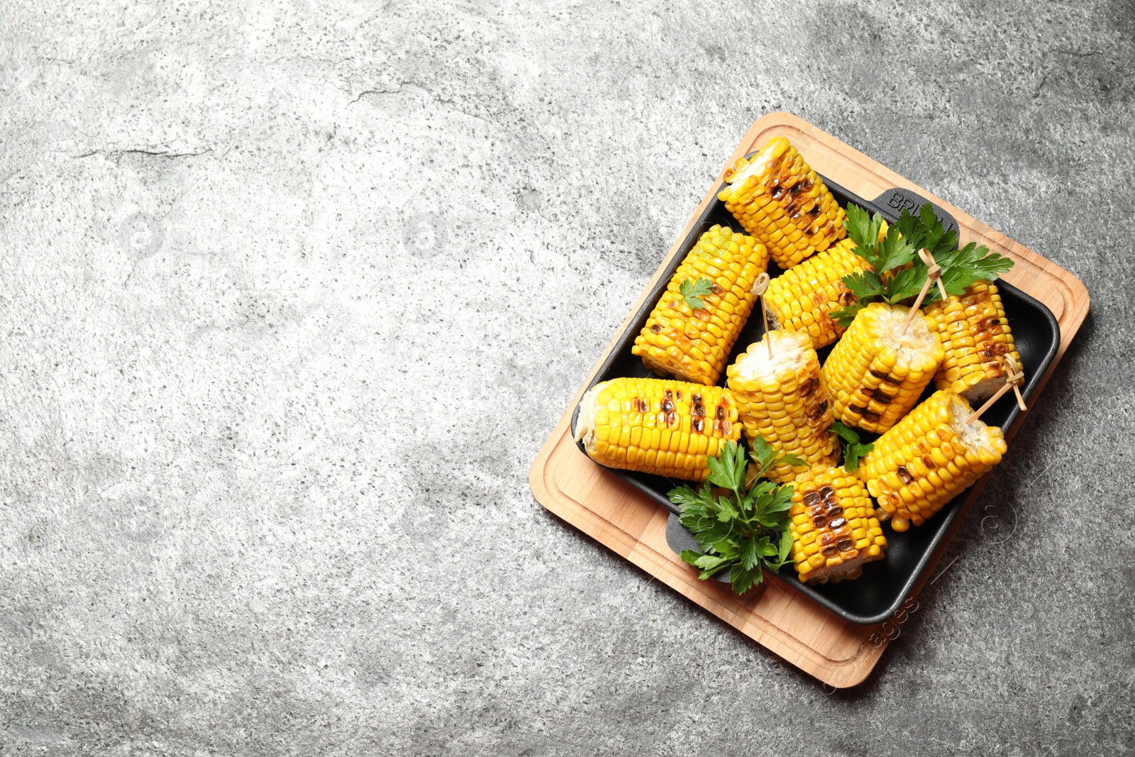 Photo of Tasty grilled corn on grey table, top view. Space for text