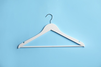 Photo of Empty wooden clothes hanger on color background, top view