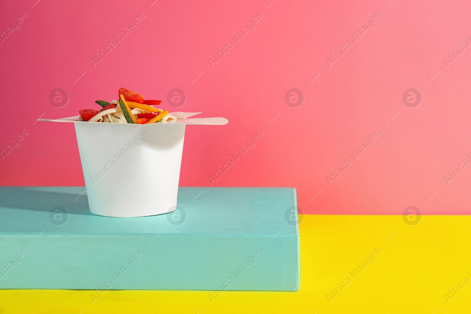 Photo of Box of vegetarian wok noodles on color background. Space for text