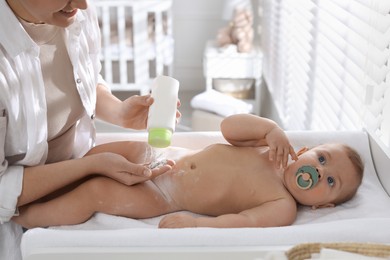 Photo of Mother applying dusting powder on her cute baby at home, closeup