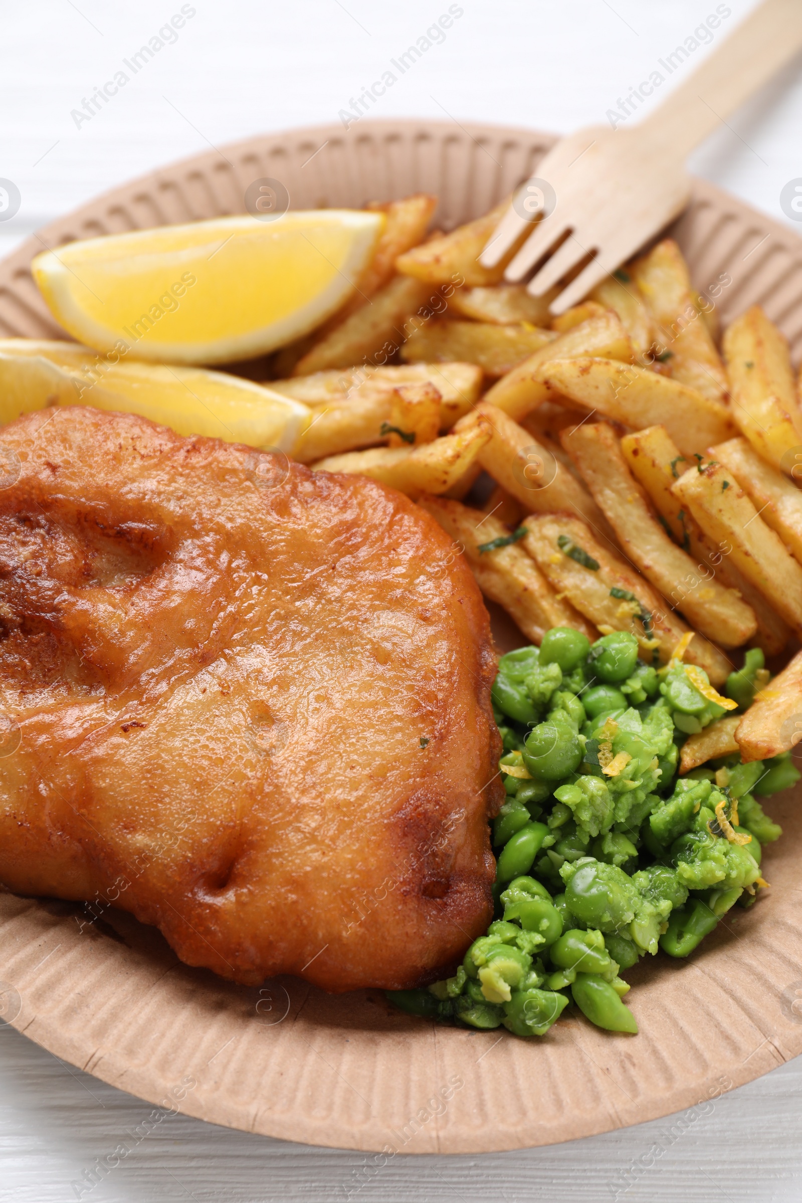 Photo of Tasty fish, chips, peas and lemon on white wooden table, closeup