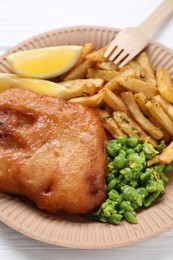 Tasty fish, chips, peas and lemon on white wooden table, closeup