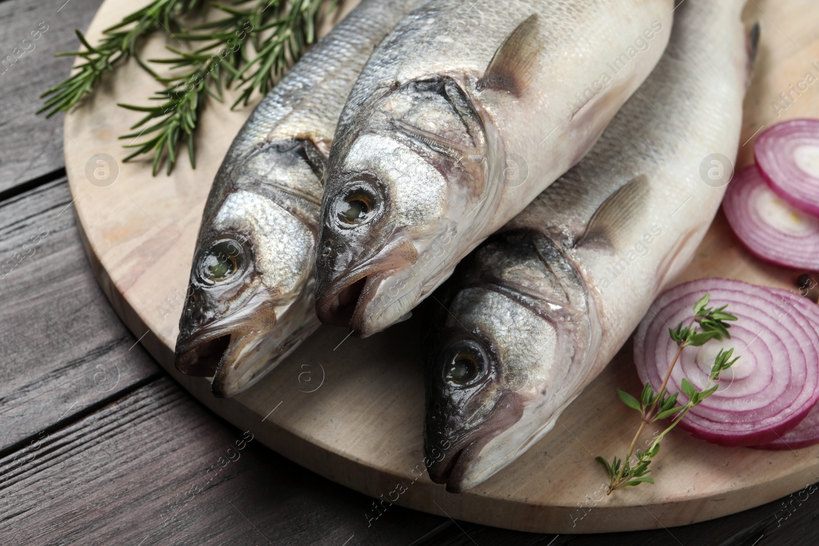 Photo of Sea bass fish and ingredients on wooden table, closeup