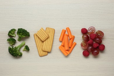 Photo of Different tasty finger foods for baby on beige wooden table, flat lay