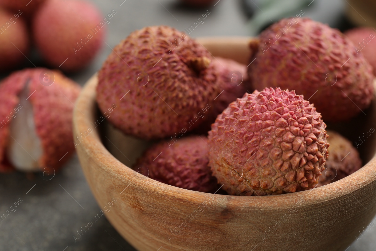Photo of Fresh ripe lychee fruits in wooden bowl on table, closeup