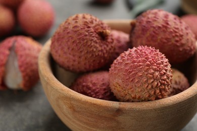 Fresh ripe lychee fruits in wooden bowl on table, closeup