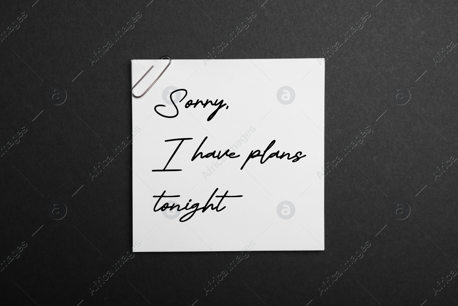 Image of White note with phrase Sorry, I Have Plans Tonight on black background, top view