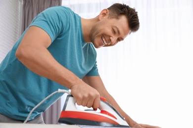 Man ironing shirt on board at home