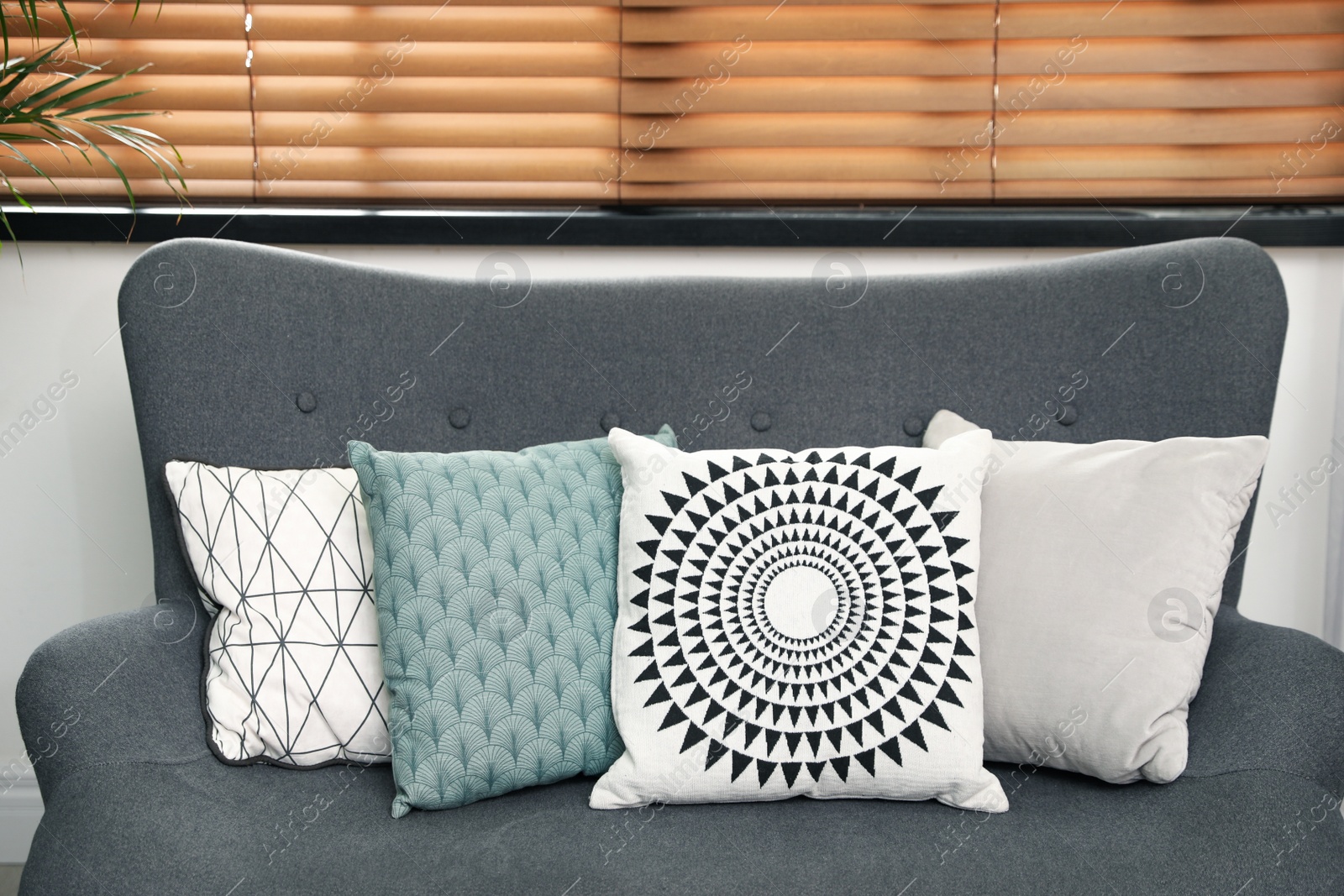 Photo of Stylish decorative pillows on grey couch indoors, closeup