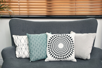 Stylish decorative pillows on grey couch indoors, closeup