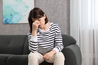 Photo of Overwhelmed woman sitting on sofa at home