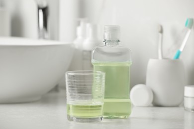 Photo of Mouthwash and glass on white countertop in bathroom