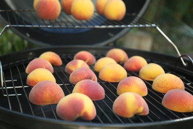 Photo of Modern grill with tasty cut peaches outdoors, closeup