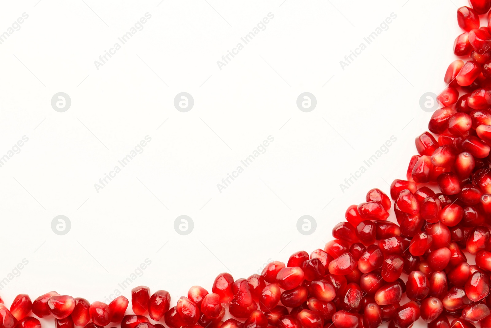 Photo of Many ripe juicy pomegranate grains on white background, flat lay. Space for text