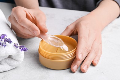 Photo of Woman using under eye patches at light table, closeup. Cosmetic product