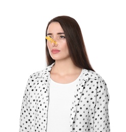 Photo of Young woman with clothespin on white background. Runny nose concept