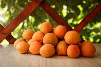 Photo of Heap of delicious ripe apricots on wooden table outdoors