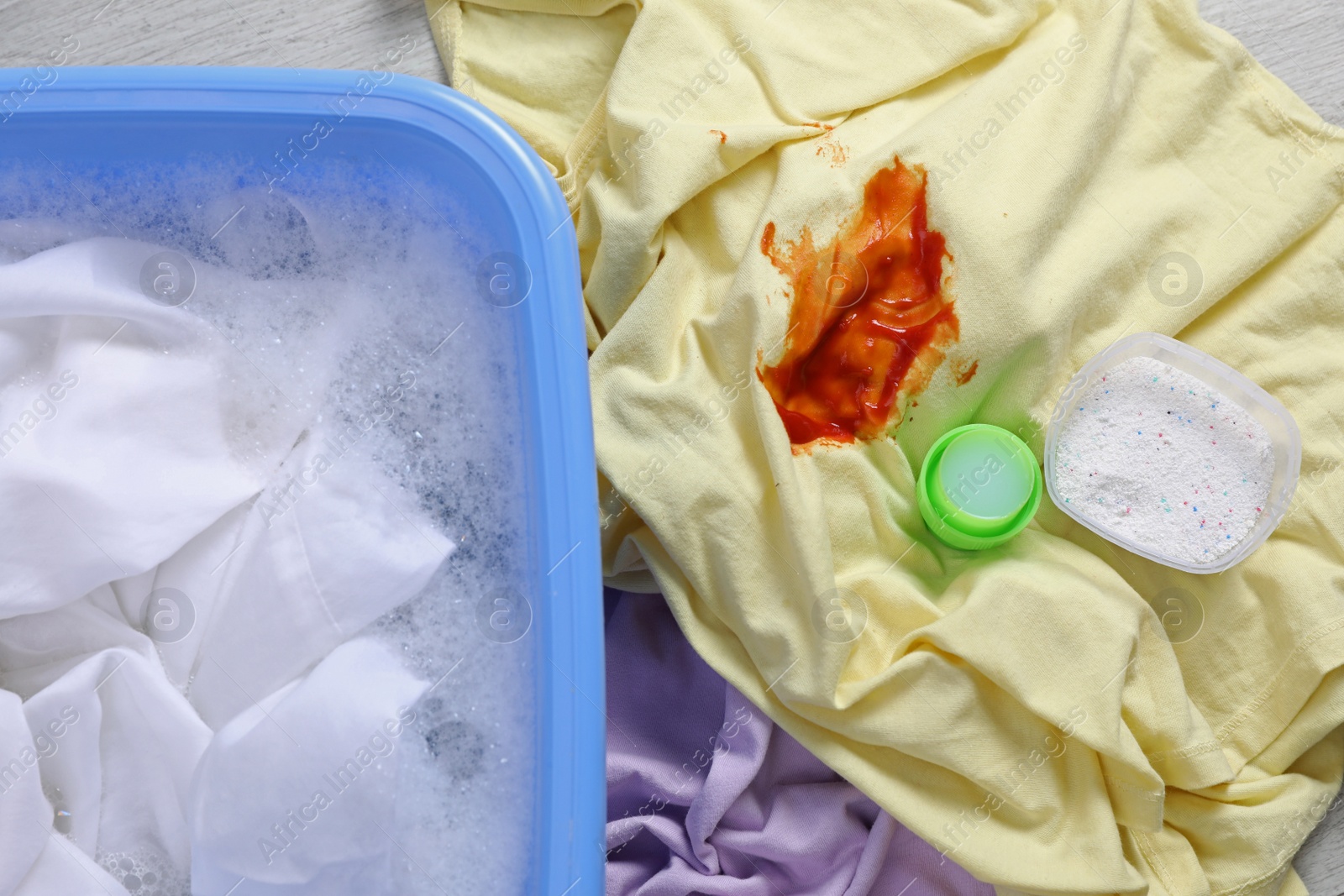 Photo of Dirty garment and detergent near basin with white shirt, top view. Hand washing laundry
