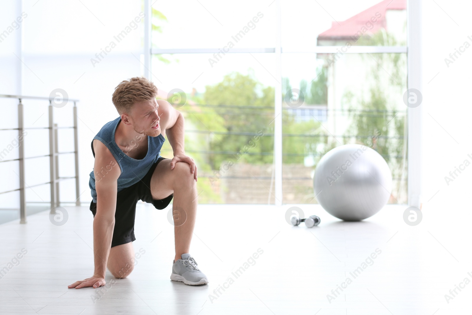 Photo of Man in sportswear suffering from knee pain at gym