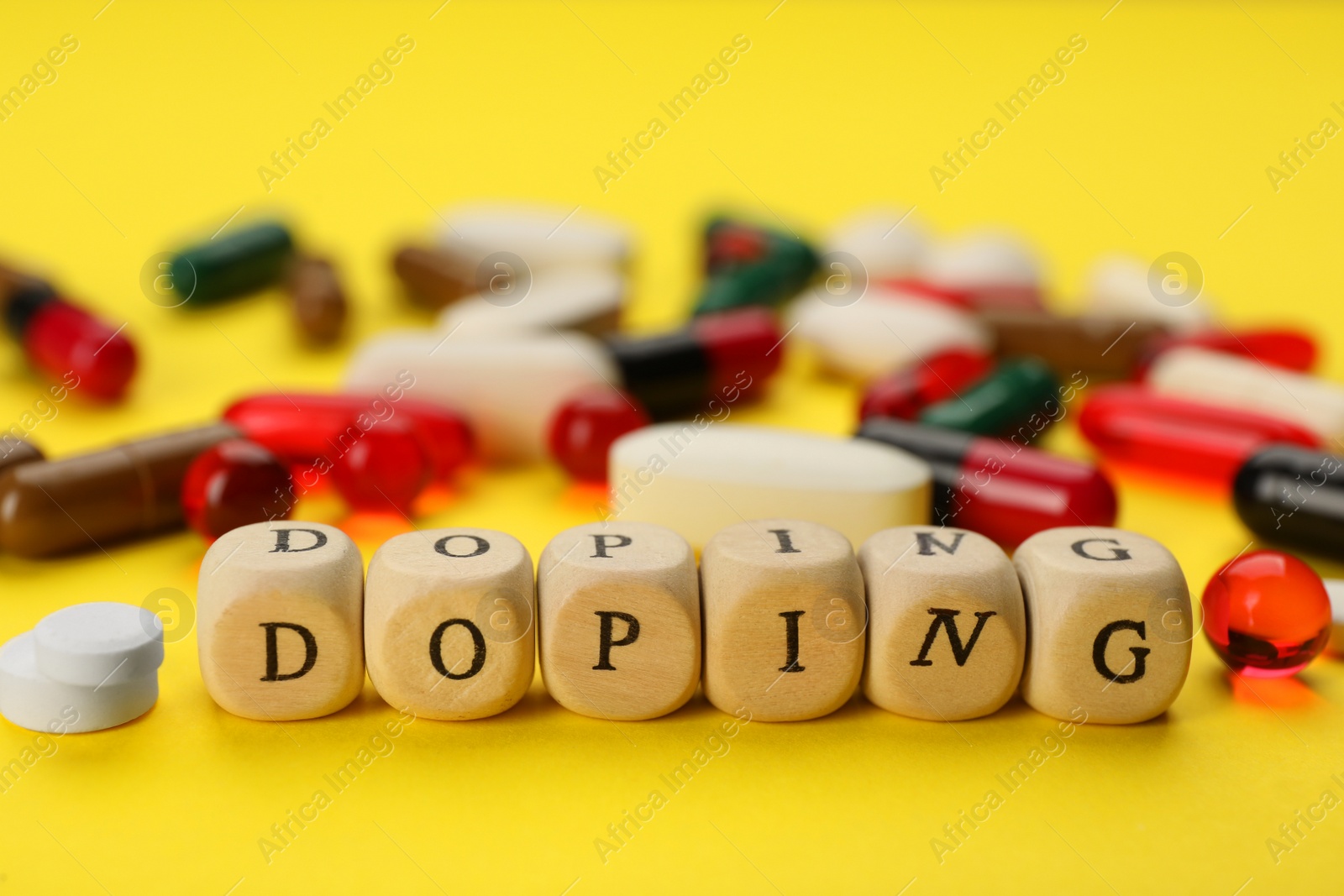 Photo of Wooden cubes with word Doping and drugs on yellow background, closeup