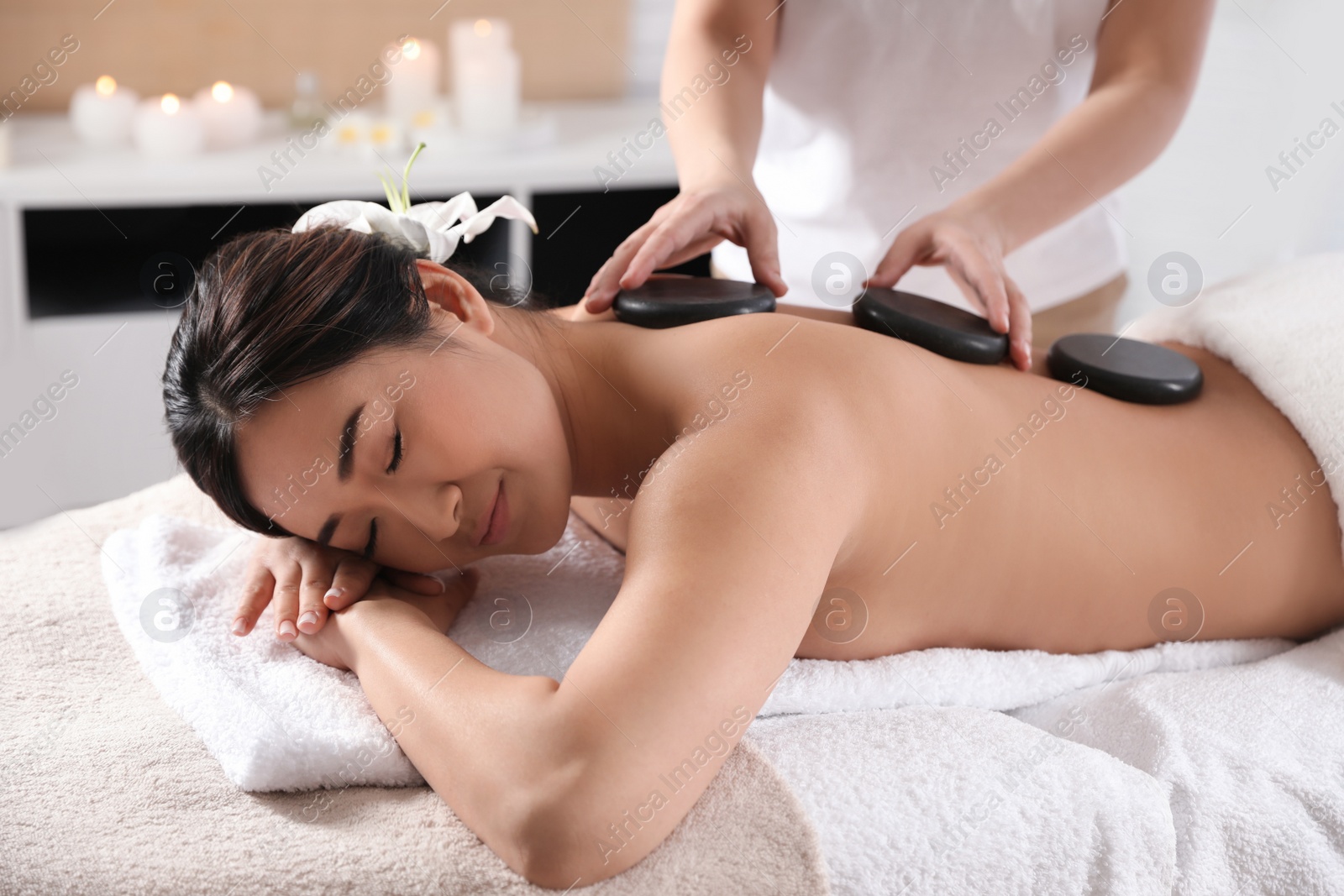 Photo of Beautiful Asian woman getting hot stone massage in spa salon