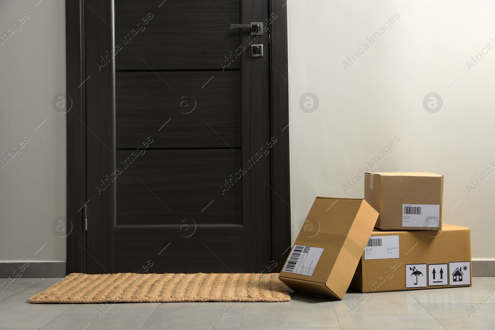 Photo of Cardboard boxes on floor mat near entrance. Parcel delivery service