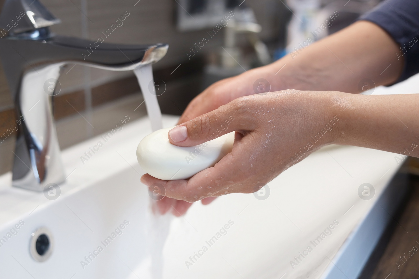Photo of Woman with soap bar washing hands in bathroom, closeup