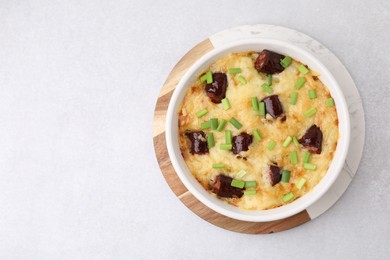 Photo of Tasty sausage casserole with green onions in baking dish on white table, top view. Space for text