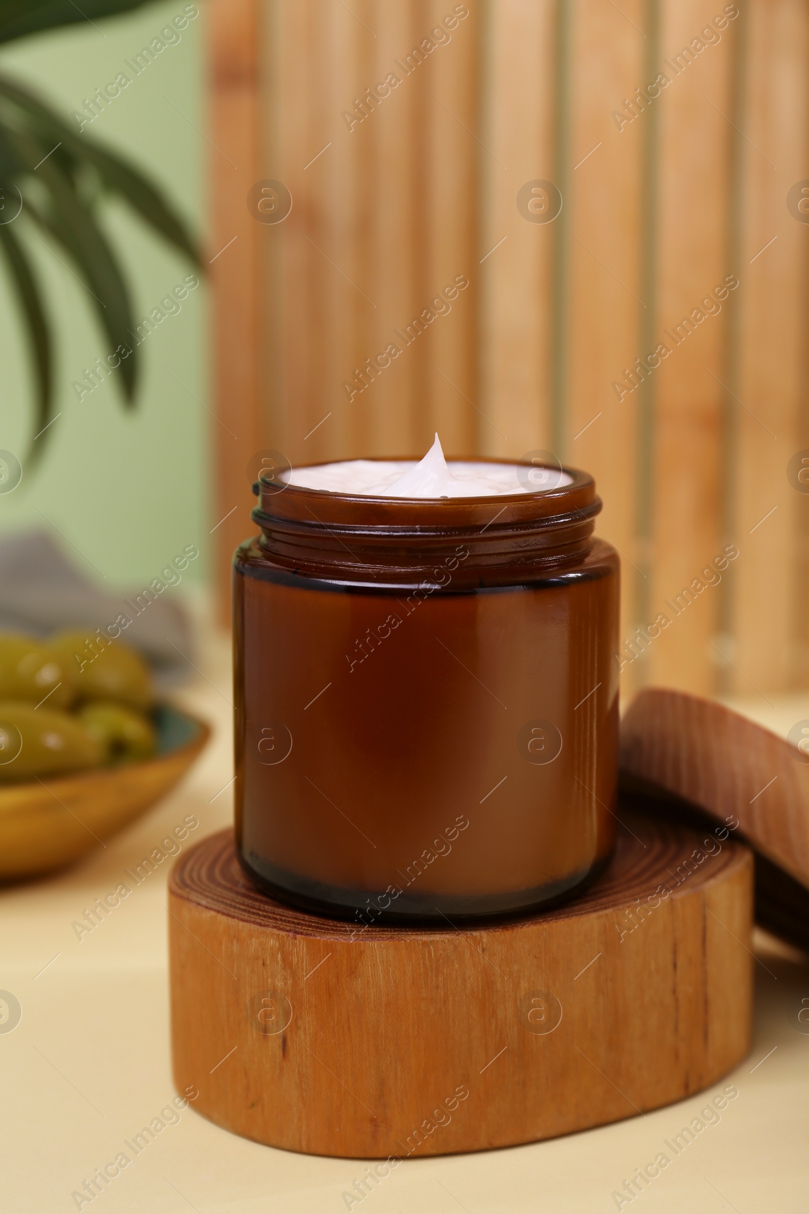 Photo of Jar of cream with olive essential oil on wooden table