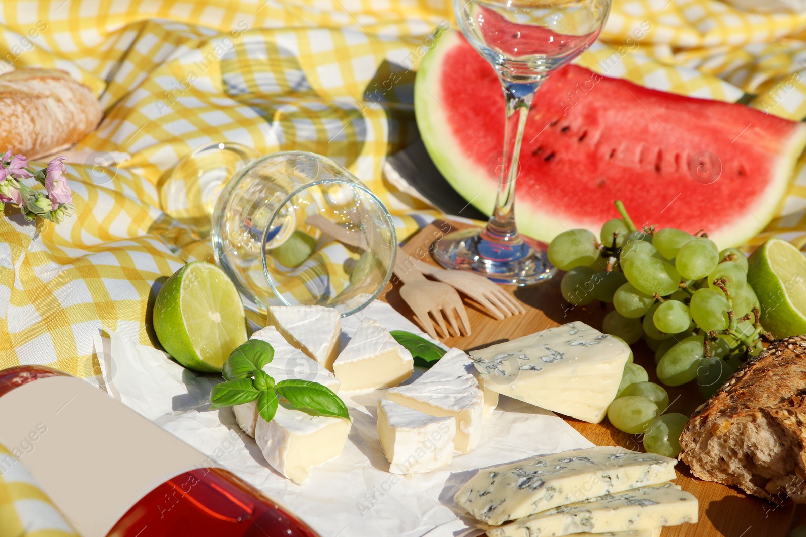 Photo of Delicious food and wine on picnic blanket, closeup