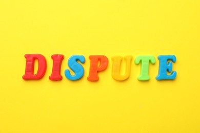 Word Dispute made of colorful letters on yellow background, flat lay