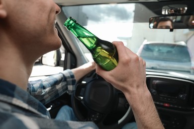 Photo of Man with bottle of beer driving car, closeup. Don't drink and drive concept