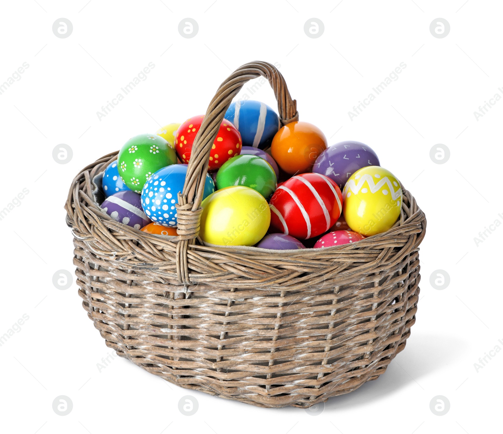 Photo of Decorated Easter eggs in wicker basket on white background