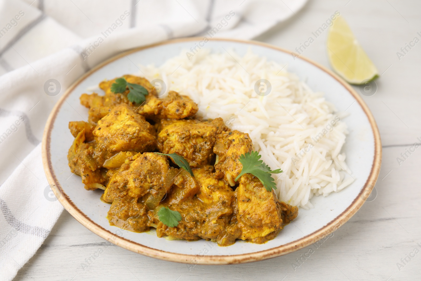 Photo of Delicious chicken curry with rice on white wooden table