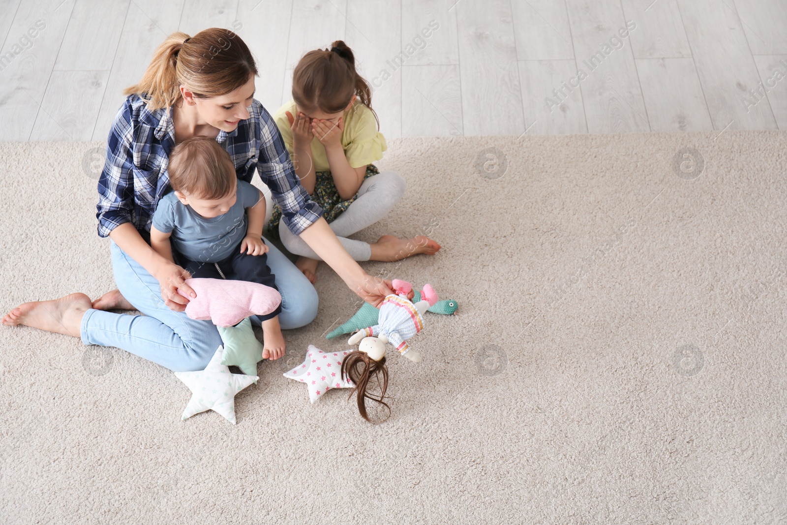 Photo of Mother with cute little children sitting on cozy carpet at home