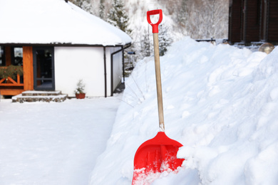 Photo of Red shovel in large snowbank on winter day