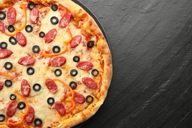 Photo of Tasty pizza with cheese, dry smoked sausages, olives and pepper on grey table, top view. Space for text