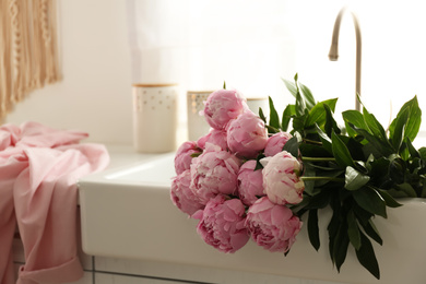 Bouquet of beautiful pink peonies in kitchen sink. Space for text