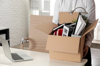 Photo of Young man with box of stuff in office, closeup