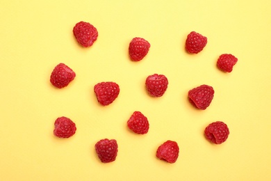 Flat lay composition with ripe aromatic raspberries on color background