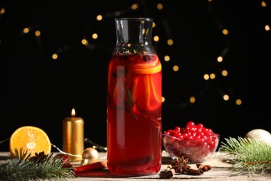 Glass bottle of aromatic punch drink, ingredients and Christmas decor on wooden table