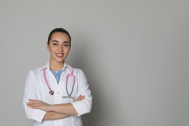 Portrait of beautiful young doctor on light grey background. Space for text